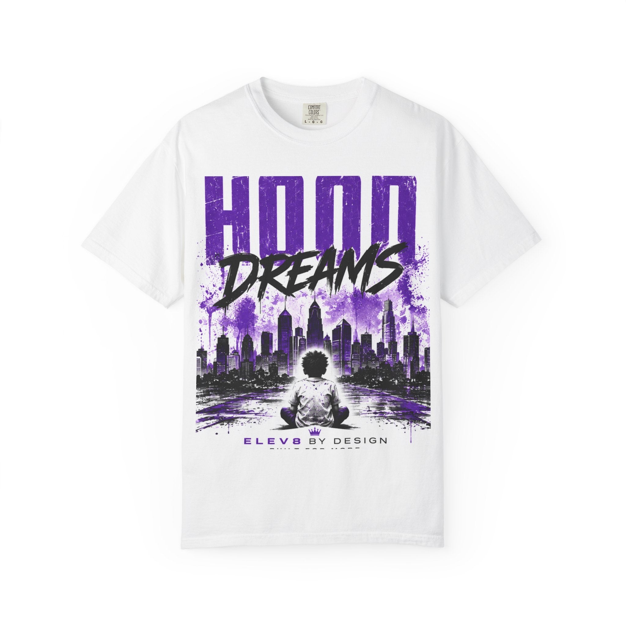 A white short-sleeve crewneck t-shirt featuring a purple and black graphic print on the front with the text 'HOOD DREAMS' and a stylized city skyline.